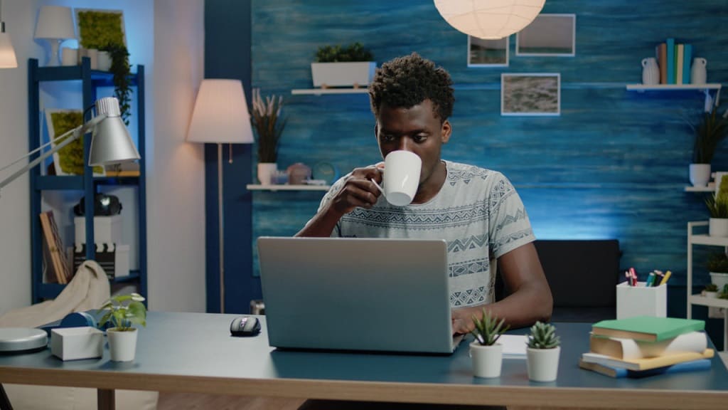 man working from home reading mail and drinking coffee